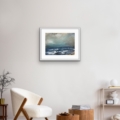 Reverberation seascape print by Louise Turnbull displayed in a white frame above a contemporary cream chair and wooden tables.