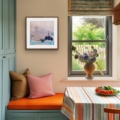 Gold Threads still life giclée print shown in a wooden frame above orange seating in a kitchen with teal cupboards